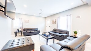 A modern living room with a sofa, ottoman, and coffee table. - The Cedar Chateau (Niagara Falls)