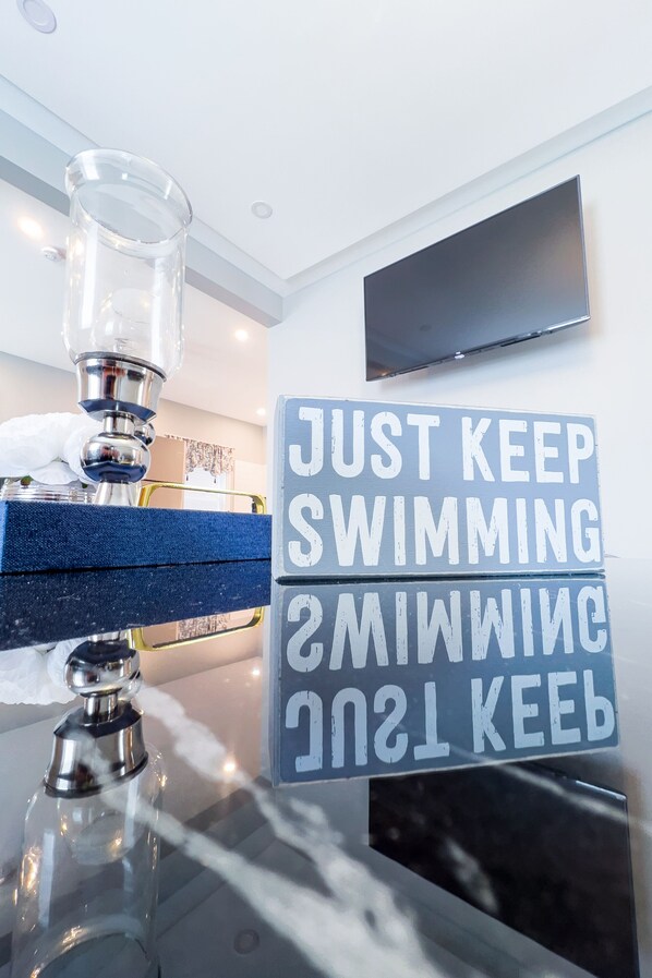 A bathroom with a glass container, a blue towel, and a motivational sign.