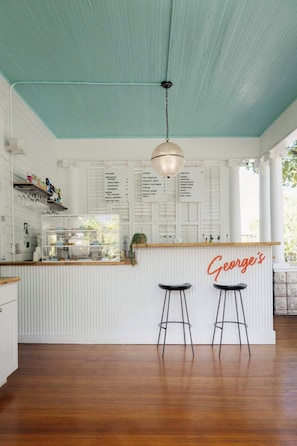 Een keuken met een blauwgroen plafond, witte kastjes, een bar met krukken en een hanglamp.