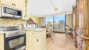 A spacious kitchen with a built-in oven and microwave, a dining area with a view of the city, and a balcony with ornate furniture.