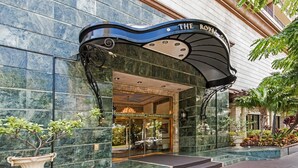 The entrance to The Royal Garden at NDH, featuring a marble facade and a curved awning with the hotel's name.