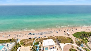 Un complexe hôtelier en bord de mer doté d’une piscine, de chaises longues et offrant une vue sur l’océan.