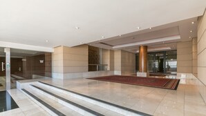 A spacious lobby with marble flooring, a red carpet, and a staircase leading to an upper level. - Raphael Penthouse | Square and Mall and Pool Access (Johannesburg)