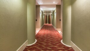 A hotel hallway with a red carpet, beige walls, and recessed lighting. - Raphael Penthouse | Square and Mall and Pool Access (Johannesburg)