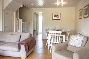 A cozy living room with two sofas, a dining table with chairs, and a staircase leading to another room.