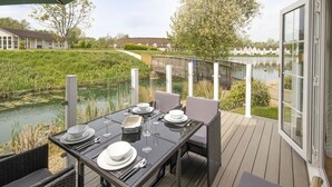 Een eettafel voor vier personen met uitzicht op een meer en een houten terras.