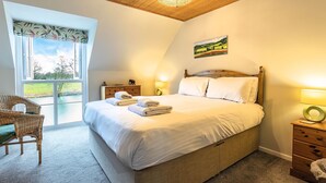Una camera da letto con un letto, una sedia, un comodino, una lampada e un quadro appeso al muro.