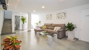 A modern living room with a sofa, coffee table, and potted plants.