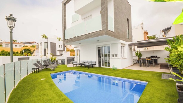 A modern two-story house with a swimming pool, outdoor seating, and a well-maintained lawn.