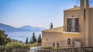 A two-story building with a balcony, a pool, and a view of mountains.