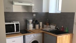 Una cocina compacta equipada con microondas, cafetera y lavadora.