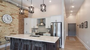 A modern kitchen with a central island, bar stools, and pendant lighting.