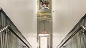A staircase with a view of a building through a window above.