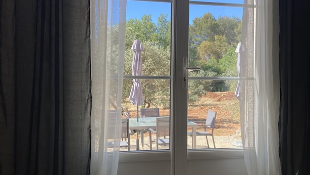Une pièce dotée d’une porte-fenêtre coulissante donnant sur un espace extérieur aménagé avec des tables et des chaises.