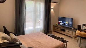 Une chambre à coucher avec un lit, une télévision, une horloge et une fenêtre avec des rideaux.