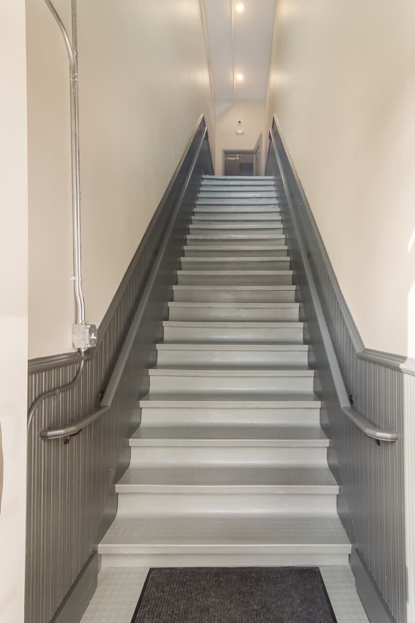 Un escalier moderne avec une rampe, menant à l’étage supérieur.
