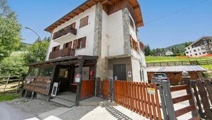A two-story building with a wooden facade, a balcony, and a visible entrance. - Miramonti 21 Ski In - Ski Out (Sauze d'Oulx)