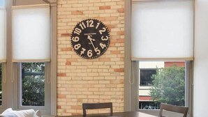 A dining area with a brick wall, a large clock, and a view of the outside. - Golden Lofts Unit 3 Downtown Traverse City 2bd/2ba (Traverse City)