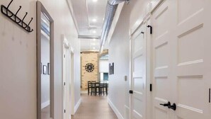 A hallway with white doors, a patterned rug, and a wall-mounted coat rack. - Golden Lofts Unit 3 Downtown Traverse City 2bd/2ba (Traverse City)