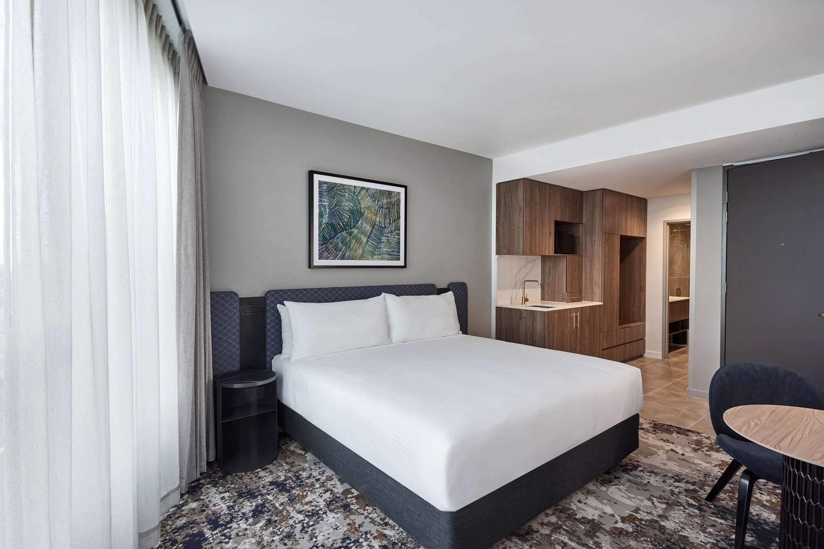 Une chambre d’hôtel avec un grand lit, une table de chevet, une chaise, un bureau et une armoire.