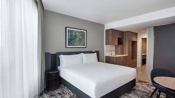 Une chambre d’hôtel avec un grand lit, une table de chevet, une chaise, un bureau et une armoire.