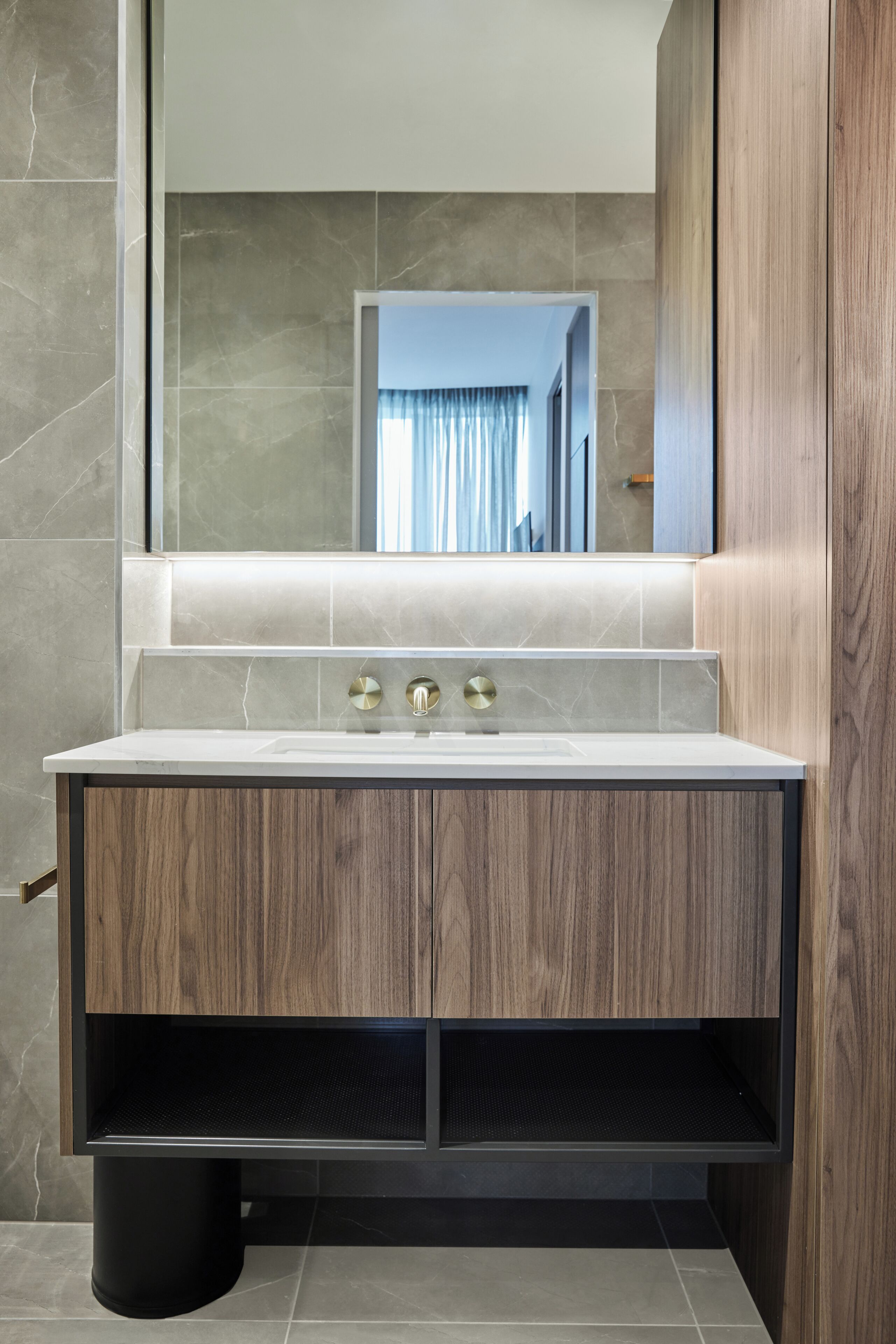 A modern bathroom with a marble vanity, a large mirror, and a view of a hallway.