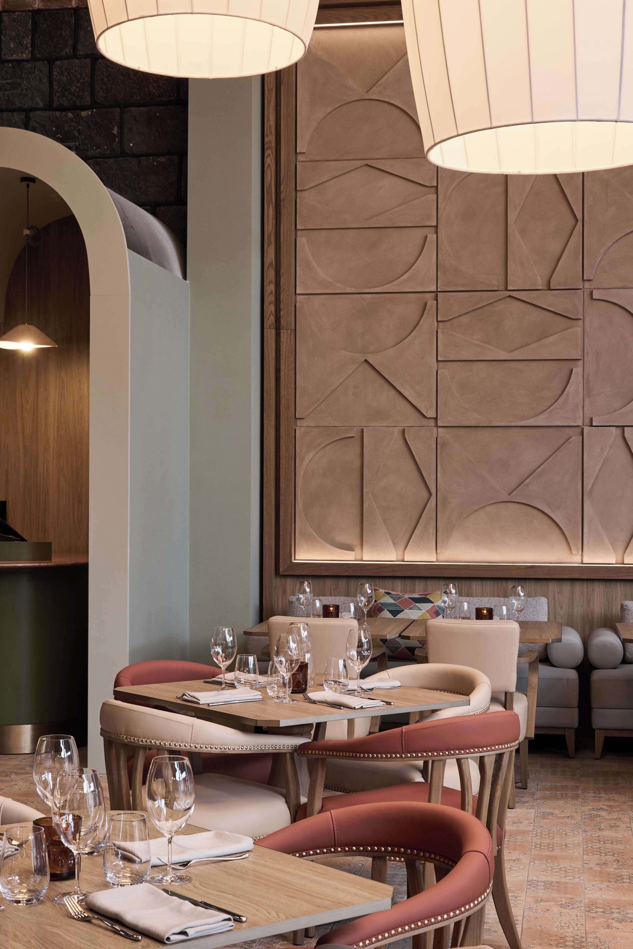 A dining area with a round table, cushioned chairs, and pendant lighting.