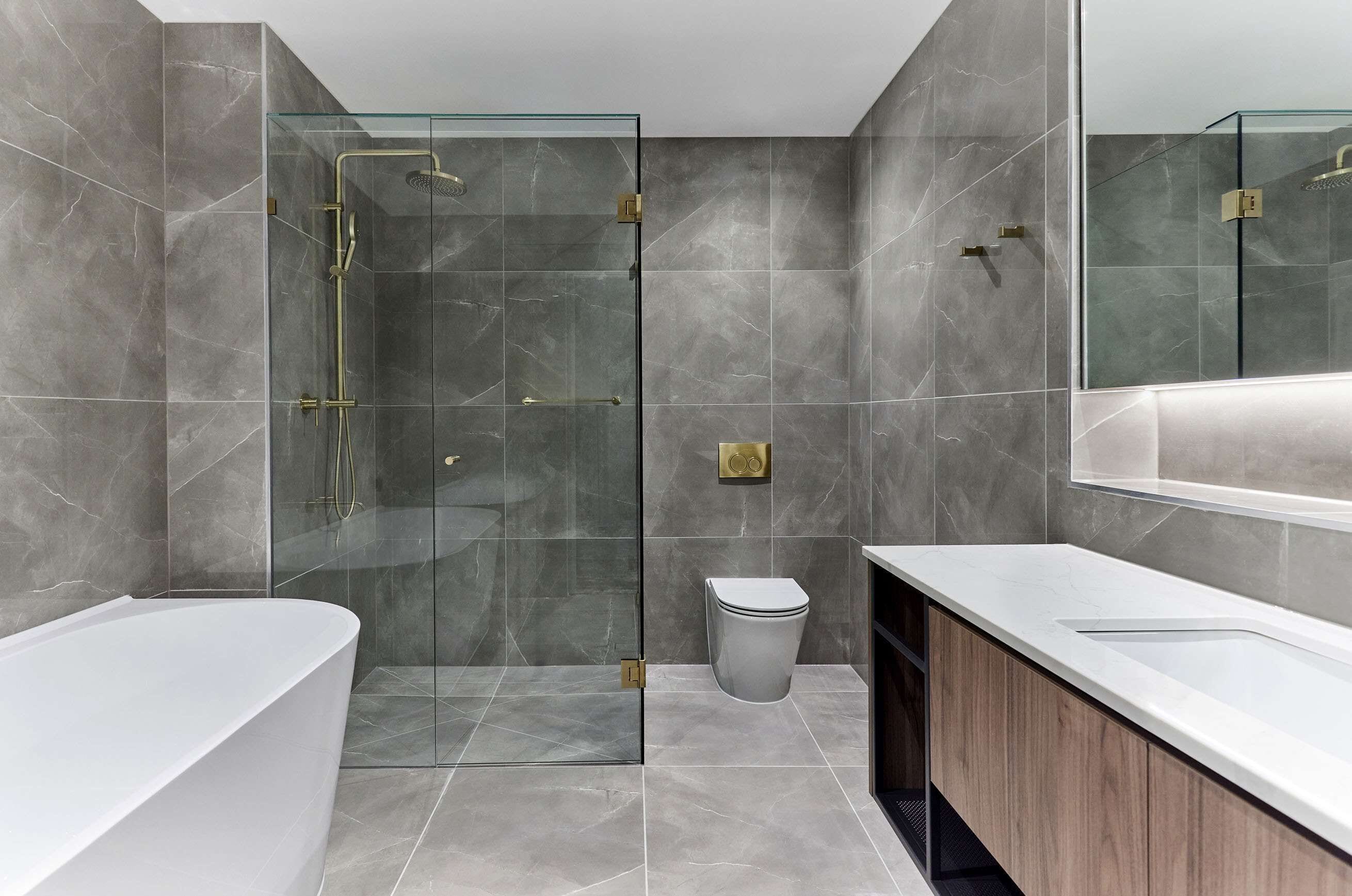 A modern bathroom with a glass-enclosed shower, a white bathtub, and a wooden vanity.