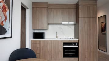 Una cocina moderna con armarios de madera, microondas, lavamanos y lavavajillas.