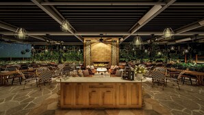A spacious indoor dining area with a central wooden bar, multiple seating arrangements, and a fire feature. - Adina Apartment Hotel Melbourne Pentridge (Coburg)