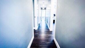 A narrow hallway with a dark wooden floor and white walls. - The Griffon House (Niagara Falls)