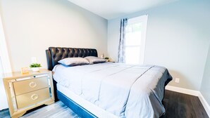 A bedroom with a bed, a nightstand, and a dresser. - The Griffon House (Niagara Falls)
