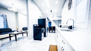 A modern kitchen with white cabinetry, a black refrigerator, and a stainless steel sink. - The Griffon House (Niagara Falls)