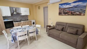 Un espacio habitable compacto con kitchenette, comedor y sofá.