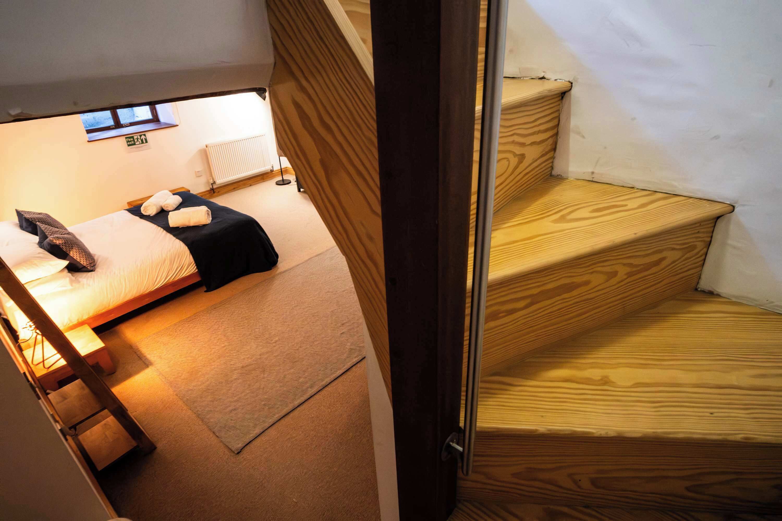 Ein Schlafzimmer mit einem Bett, einem Nachttisch, einer Lampe und einem Fenster.