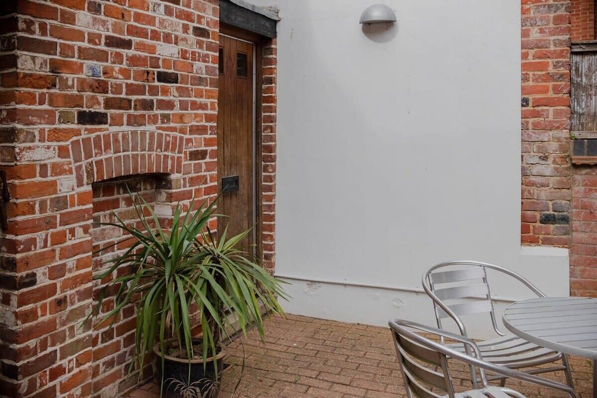 A brick wall with a door, a potted plant, and a metal table and chair set.