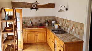 A kitchen with wooden cabinets, a tiled backsplash, and a hanging light fixture. - Gîte "Chez Nicole" in the heart of the Loire castles (Restigné)