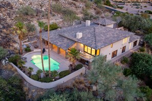 Ein modernes Haus mit Swimmingpool, umgeben von einem angelegten Garten und einer hügeligen Landschaft.