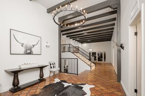 Ein modernes Interieur mit einer Treppe, einer Kristallleuchtre, einem Kuhfellteppich und einem gerahmten Kunstwerk.