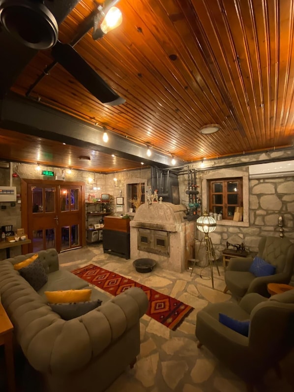 A cozy room with a stone fireplace, wooden ceiling, and comfortable seating.
