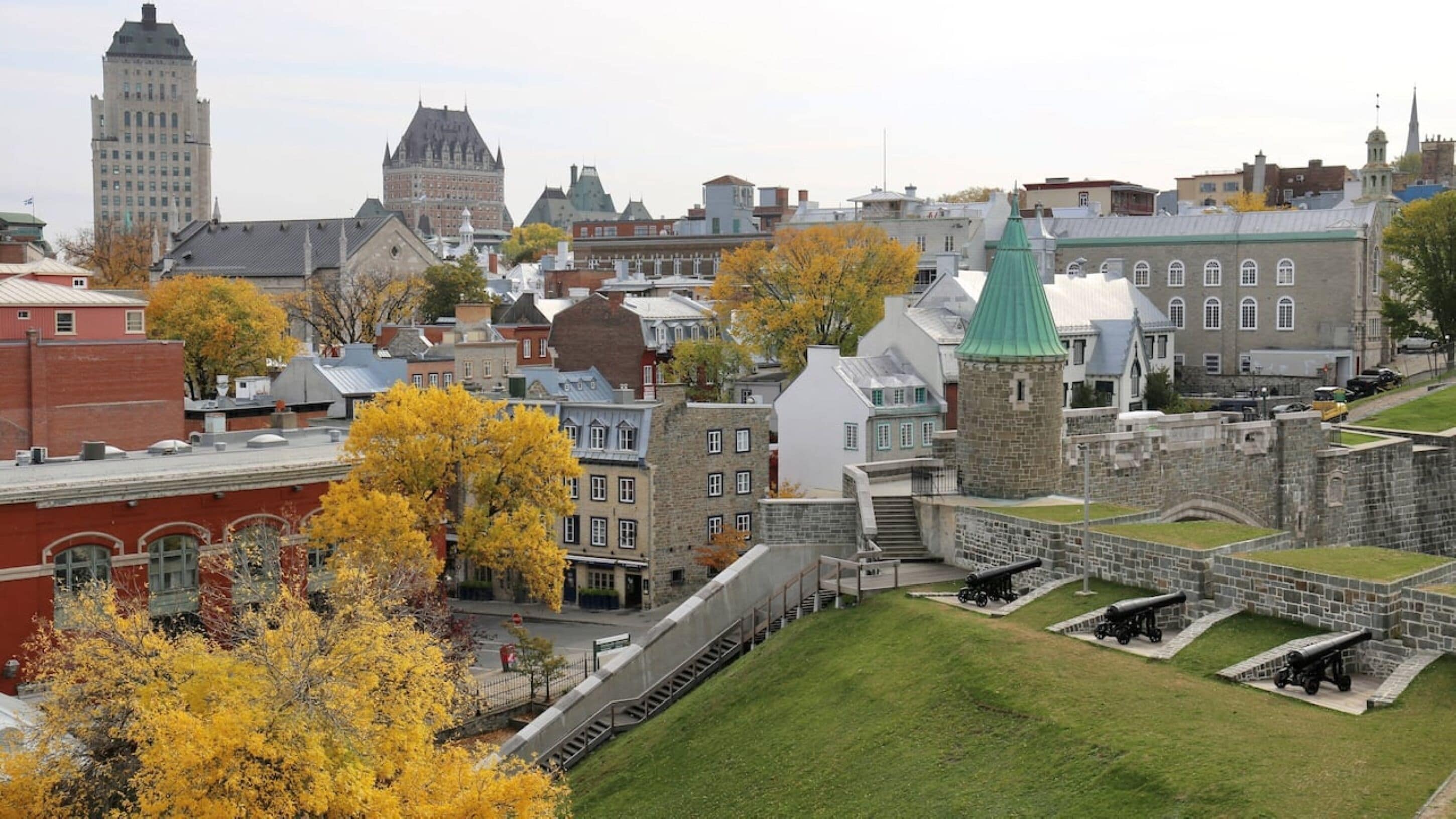 A historic fort with cannons, surrounded by autumn-colored trees and traditional buildings.