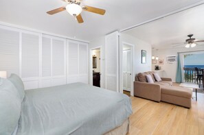 Ein Schlafzimmer mit Bett, einer Couch, einem Deckenventilator und Meerblick vom Balkon.