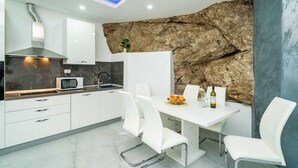 Eine moderne Küche mit weißen Schränken, einer Mikrowelle und einem Essbereich mit Tisch und Stühlen.