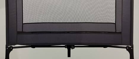 A black, rectangular, freestanding object with a mesh screen, likely a portable heater or air purifier, mounted on a black metal frame with four legs.