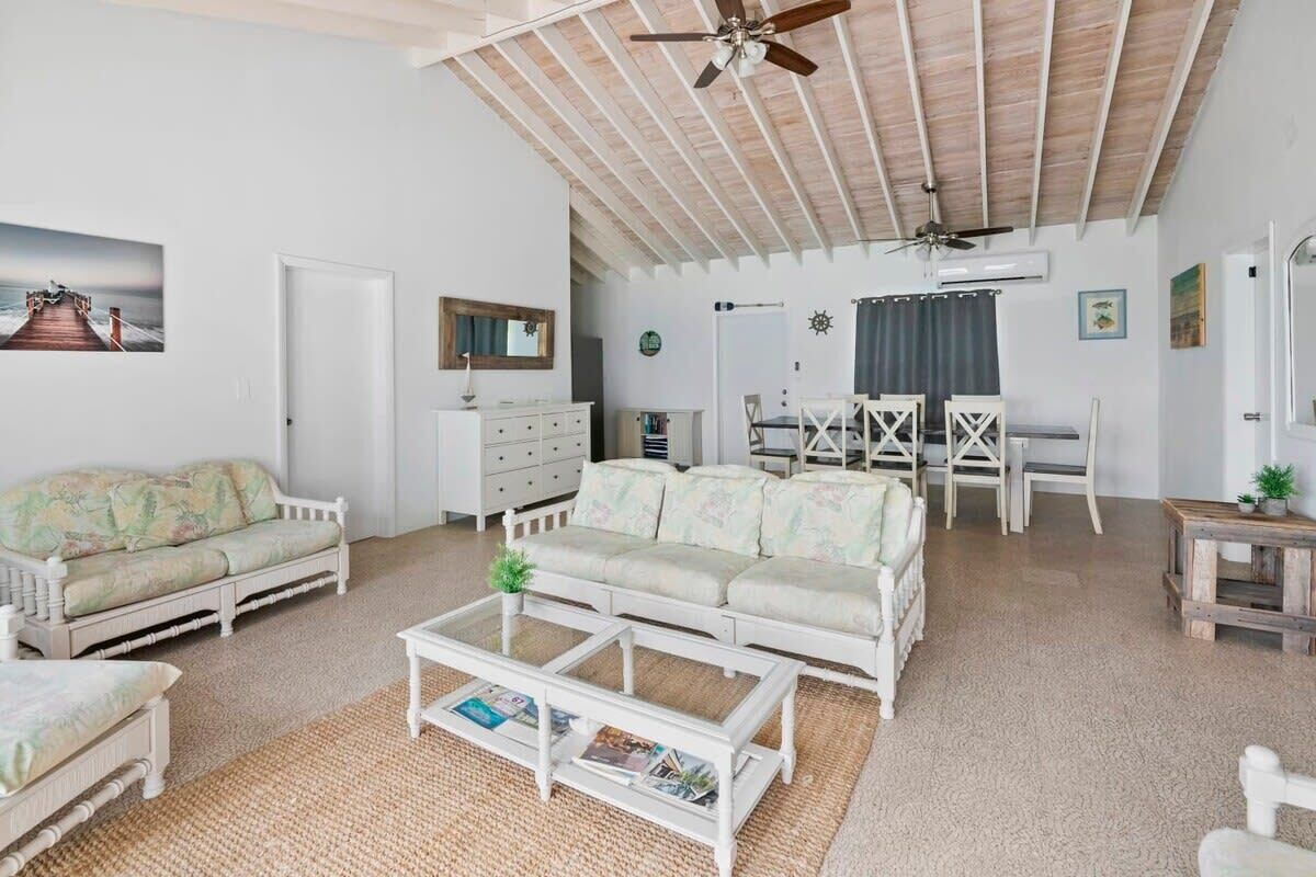 A spacious living room with a high ceiling, white furniture, and a ceiling fan.