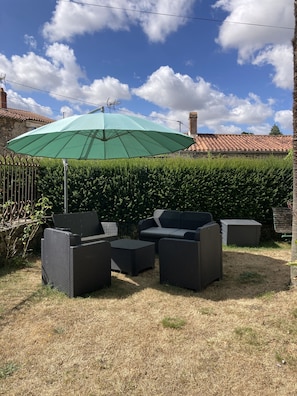 Uma área de pátio com móveis de exterior e um guarda-sol verde.