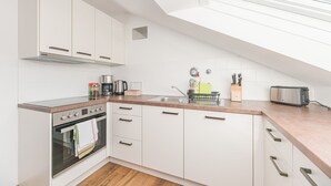 Eine moderne Küche mit weißen Schränken, einem eingebauten Backofen, einer Arbeitsplatte mit einem Toaster und einem Fenster über der Spüle.