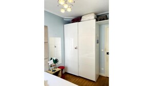 Un dormitorio con armario, escritorio con lámpara y cama.