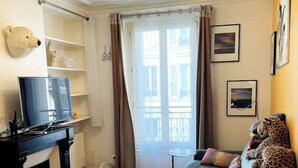 Una sala de estar acogedora con un sofá verde, un televisor y una decoración de cabeza de oso en la pared.