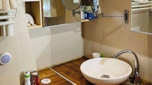 Un baño con tocador de madera, lavabo blanco y espejo.